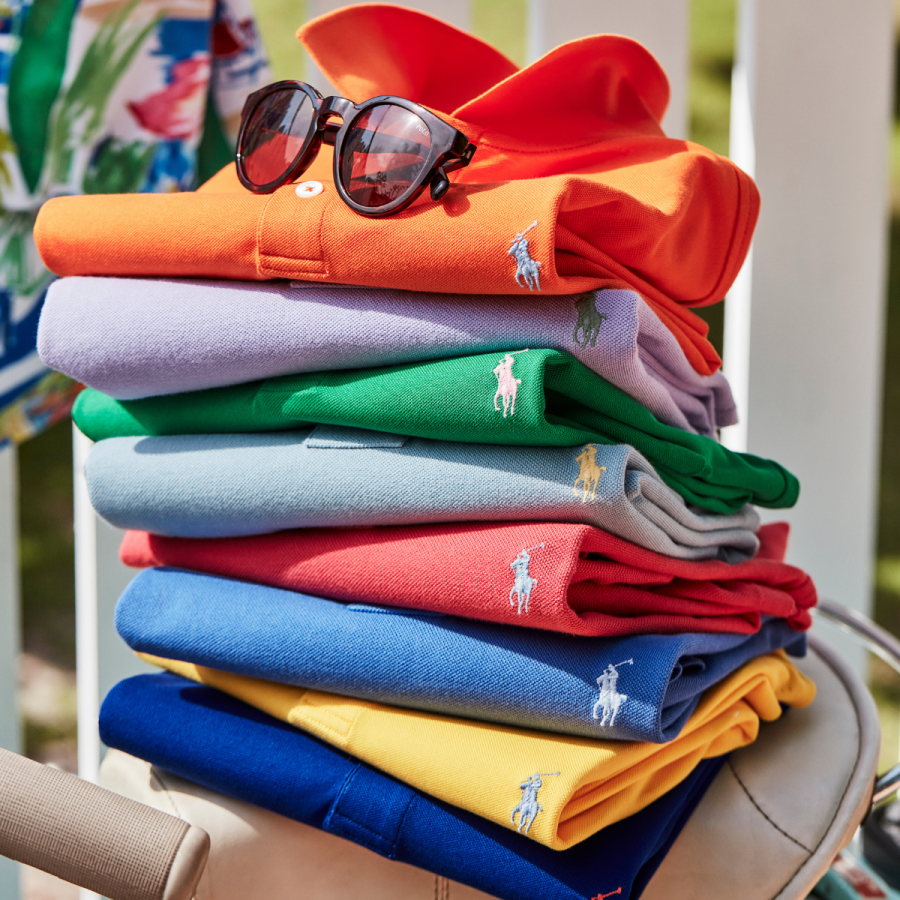 Pile of brightly coloured folded polo shorts with sunglasses on top