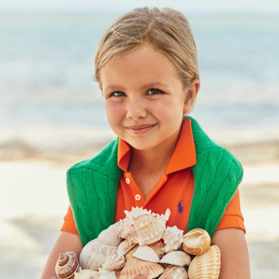 Child wearing orange polo holding shells