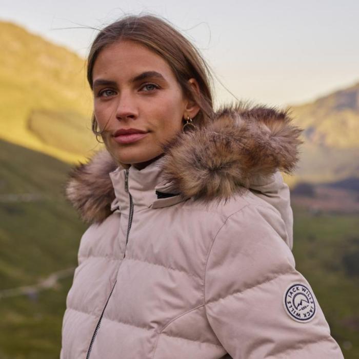 Model outdoors wearing a fur lined hooded puffer jacket